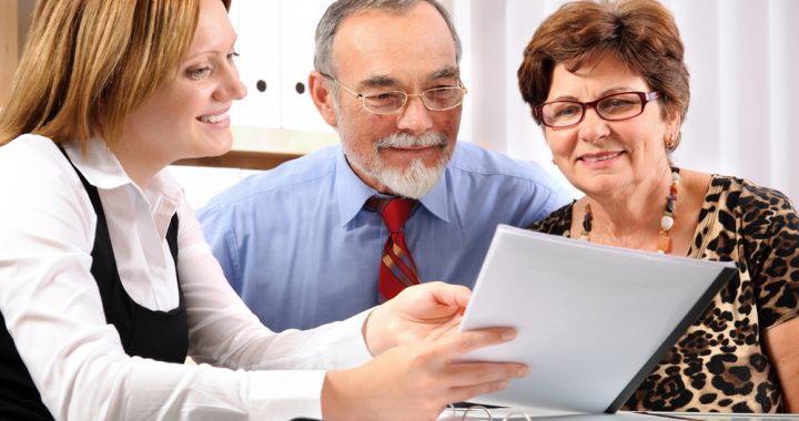 Asesora financiera explicando a una pareja mayor las opciones y beneficios de un seguro de retiro.