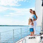 Familia disfrutando sobre la proa de un velero en navegación, representando la seguridad que brinda un seguro para lanchas y veleros.