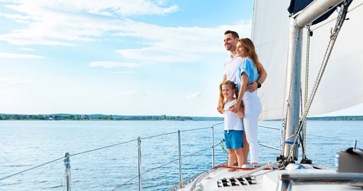 Familia disfrutando sobre la proa de un velero en navegación, representando la seguridad que brinda un seguro para lanchas y veleros.