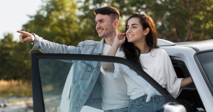 Pareja sonriente junto a un auto evalúa su próxima decisión de compra