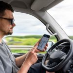 Conductor utilizando Waze o Google Maps en el celular mientras maneja