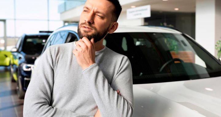 Hombre analizando vehículo en concesionaria para estimar su valor fiscal antes de comprar.